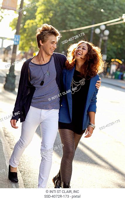Happy young couple walking down street