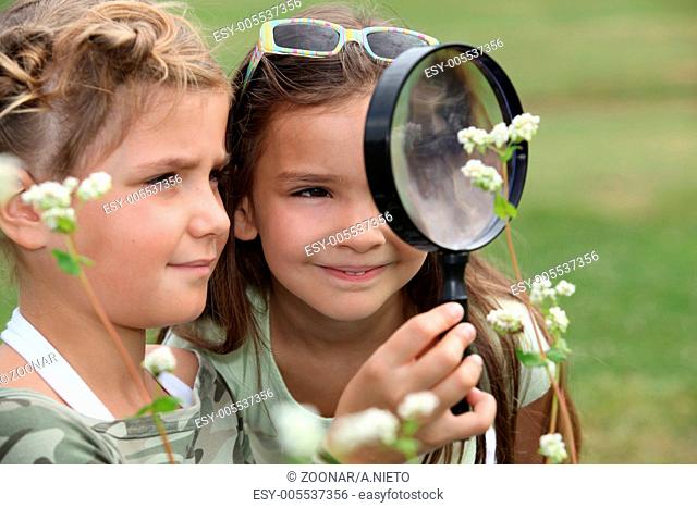 Two little girls with magnifying glasses