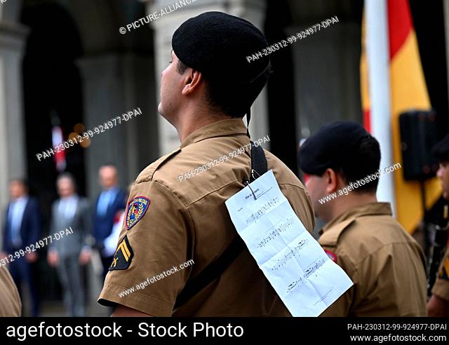 12 March 2023, Brazil, Belo Horizonte: A member of the military police band carries a sheet of music with the German national anthem on his back while Robert...