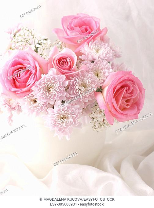 Pink and white flowers in a vase with white decorative fabric