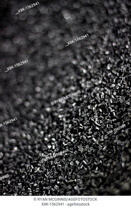 Black plastic 'nurdles' shredded plastic raw materials ready to be loaded into the hopper of a plastic molding injection machine