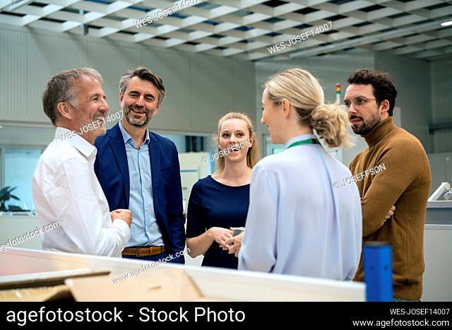 Happy business colleagues having discussion with each other at industry