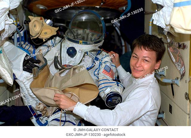 Astronaut Peggy A. Whitson, Expedition Five flight engineer, is pictured holding a Russian Sokol suit in the functional cargo block (FGB)