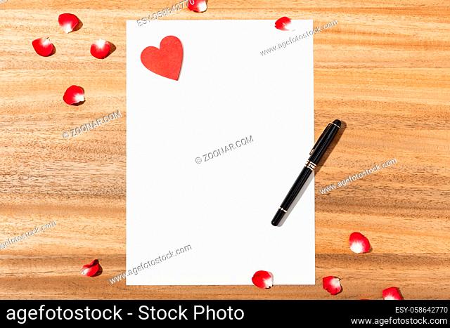 Love letter. white card, red heart shape and pen on wooden table. Flat lay. Top view. Mock up. Love concept