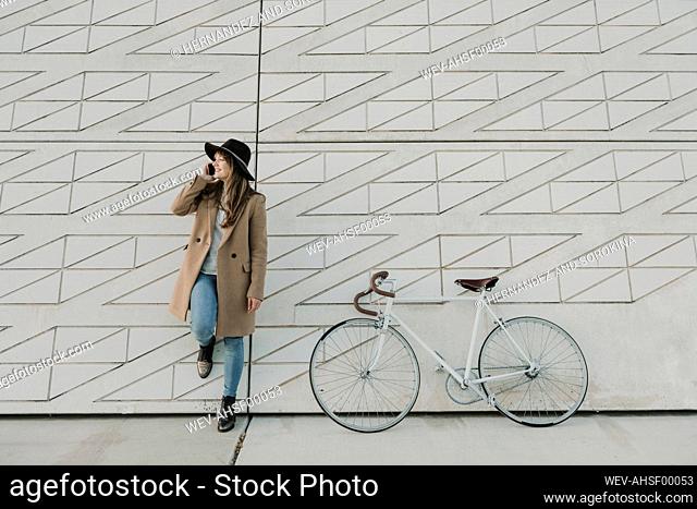 Young hipster woman speaking by phone near to a bicycle