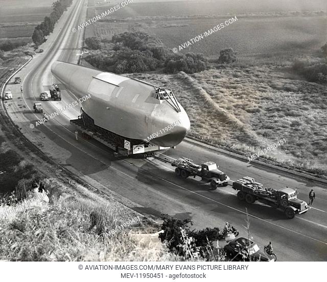 The Huge, 220 Feet Long, Wooden Hull Sub-Assembly of the Hughes H-4 Hercules / Spruce Goose on a Transporter Trailer Being Towed Along a Highway Between the...