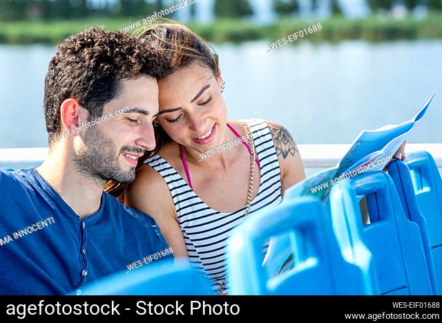 Tourist couple checking map while sitting in passenger craft