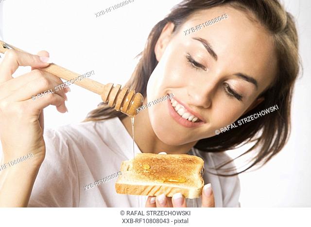Young woman eating toast with honey