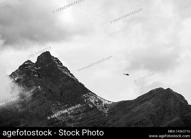 Helicopter flying through the Karwendel, in the background clouds and the Kaltwasserkar peak