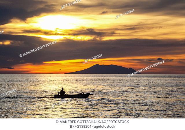 Indonesia, North Bali, sunset over the Bali Sea, seen from Lovina Beach with 1247 metre stratovolcano Mount Baluran on the distant island of Java in the...