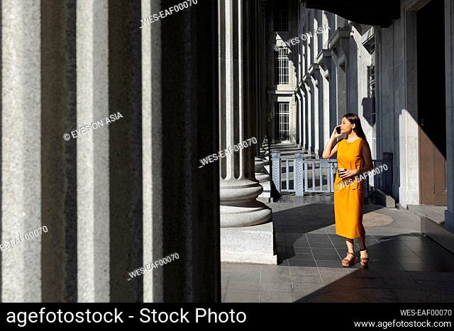 Woman talking on smart phone while standing near column at National Gallery, Singapore