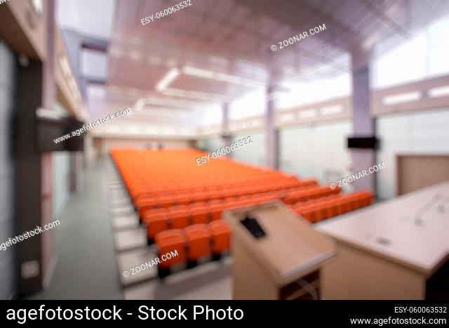 Abstract blur Rostrum with microphone and computer in conference hall. Orange color