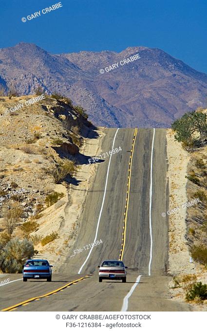 Car passing on two lane desert road approaching a hill, Anza Borrego Desert State Park, San Diego County, California