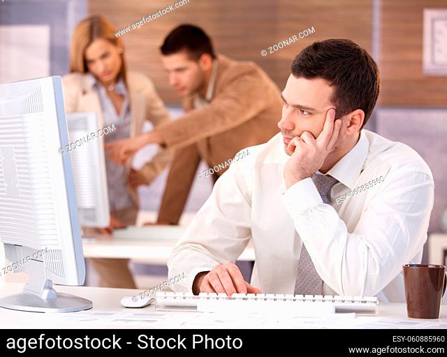 Handsome young man participating at training course, using computer