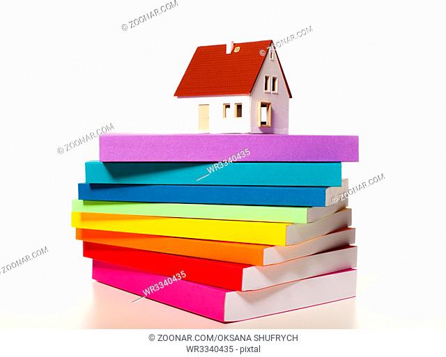 The house miniature on a stack of colorful books isolated on white background. Concept of development of a plan for construction