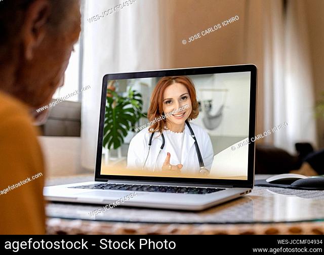 Senior woman on video call with doctor through laptop at home
