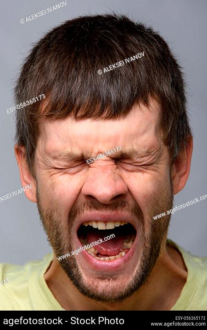 Close-up portrait of a yawning man of European appearance with wide open mouth