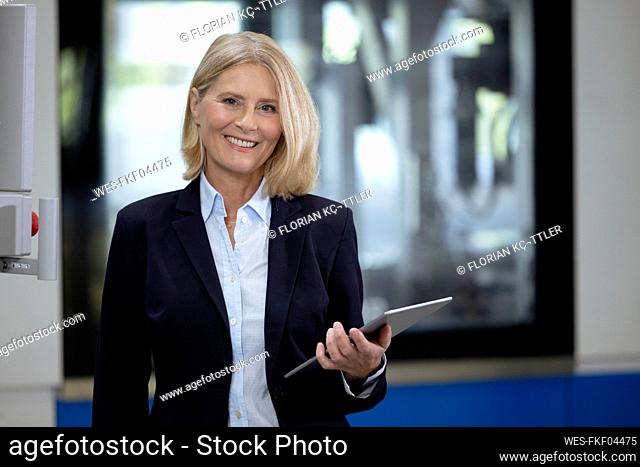 Smiling female professional holding digital tablet in factory