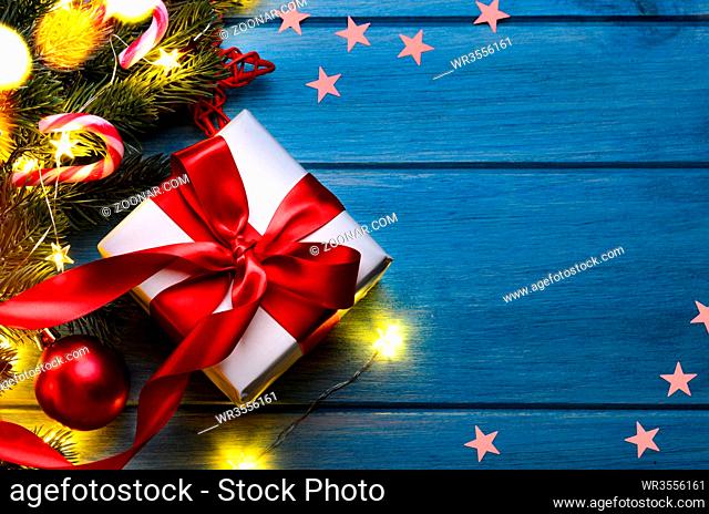 Christmas or New Year gift with festive fir tree on blue table at night