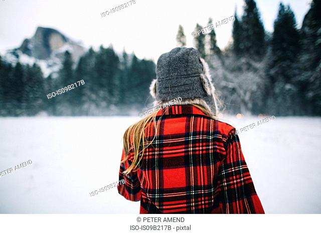 Woman wearing ushanka hat on snow-covered landscape