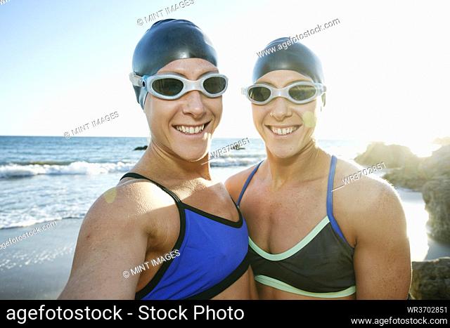 Two sisters, triathletes in training in swimwear, swimhats and goggles