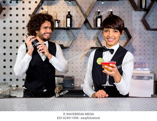 Two bartenders preparing cocktail and serving in bar counter
