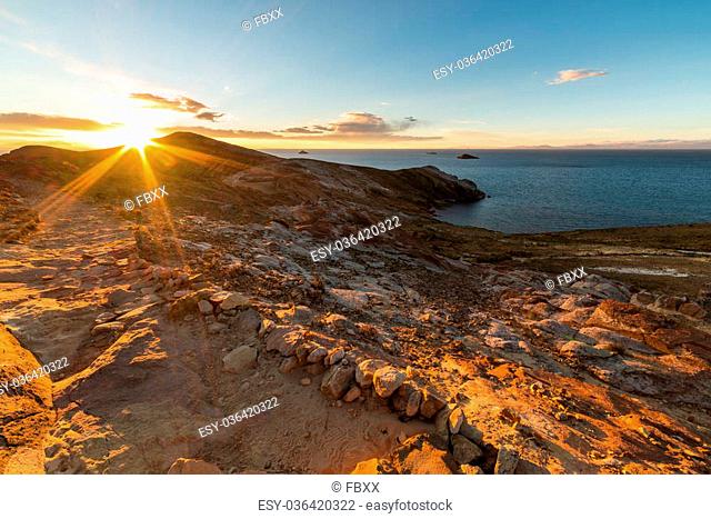 Sunset in backlight on the Island of the Sun, Titicaca Lake, among the most scenic travel destination in Bolivia. Sunstar beyond the headland with glowing rocks...