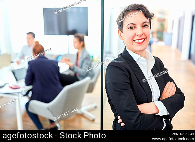 Lächelnde Business Frau als erfolgreicher Manager vor ihrem Team im Meeting