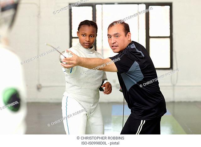Fencing tutor assisting female student