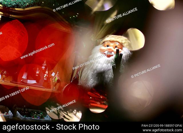 05 December 2023, Saxony-Anhalt, Derenburg: View through an illuminated Christmas tree to a Santa Claus in the Christmas exhibition of the Harzkristall glass...