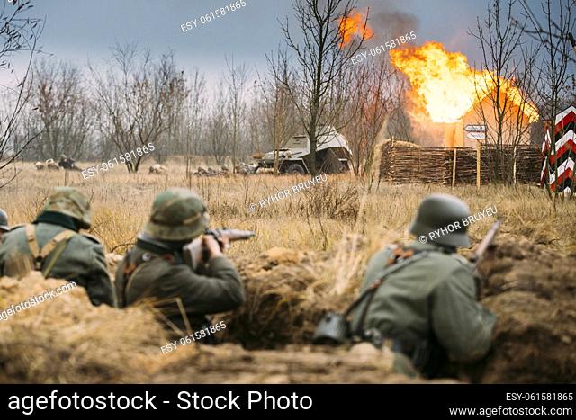 Re-enactors Armed Rifles And Dressed As World War Ii German Wehrmacht Infantry Soldiers Fighting Defensively In Trench. Defensive Position