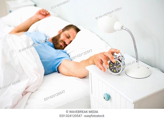 Sleeping man awakened by a alarm on bed