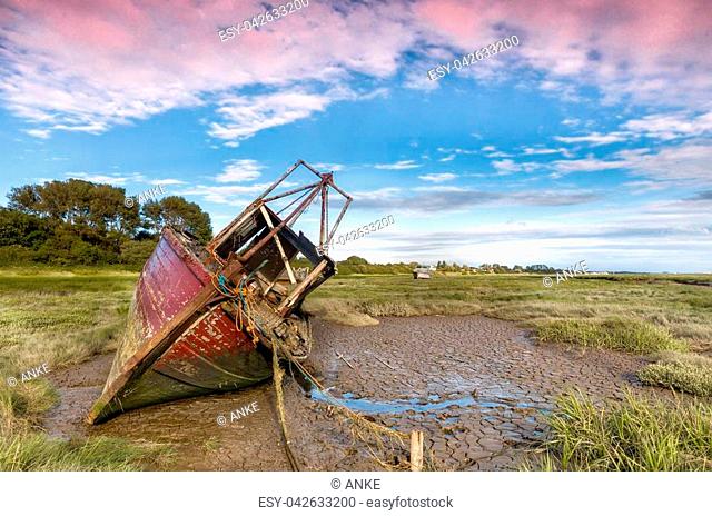 Derelict fishing boat wrecks lying in the mud flats on the riverbanks at Heswall near Liverpool