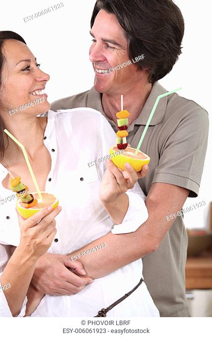 Couple in kitchen holding dessert