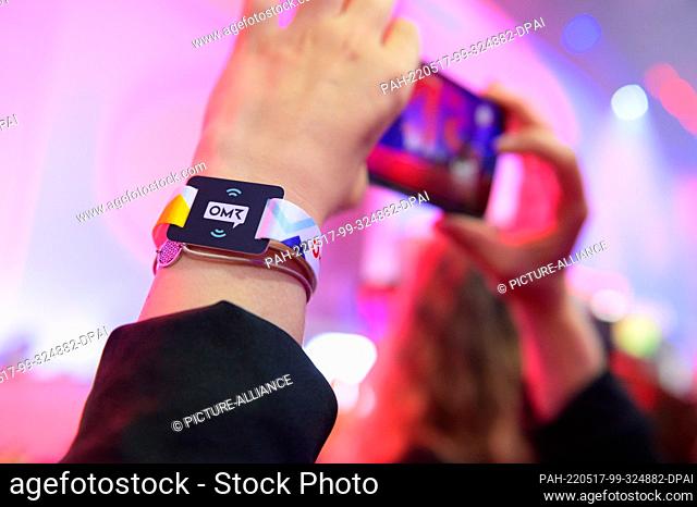 17 May 2022, Hamburg: A participant films with her cell phone and wears a wristband with an NFC chip with the inscription ""OMR""