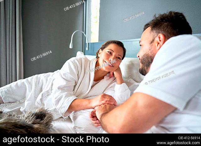 Happy affectionate couple relaxing on bed