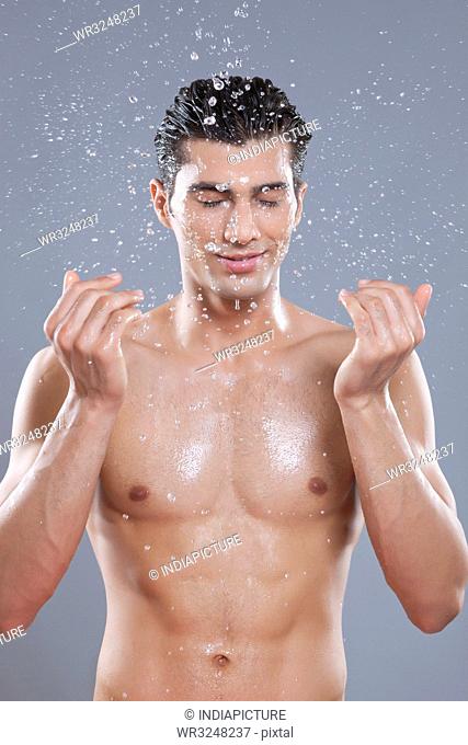 Young man splashing water on face