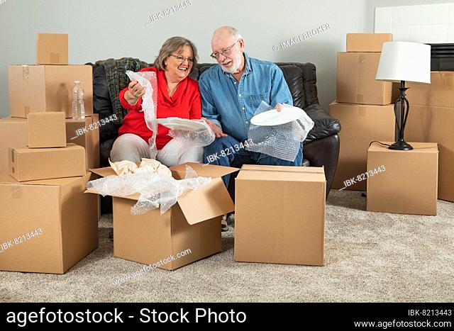 Senior adult couple packing or unpacking moving boxes