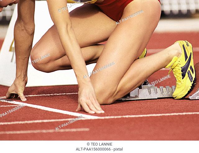 Female runner on starting block, low section, close-up