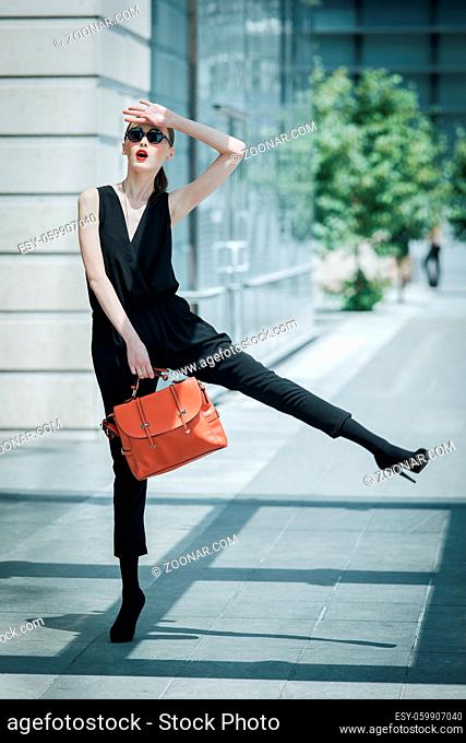 Beautiful young Asian business woman with leather bag around a glass office building