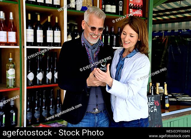 Mature couple choosing bottle of wine at a wine shop
