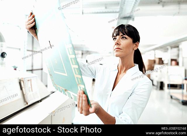 Confident female technician analyzing large computer chip in industry
