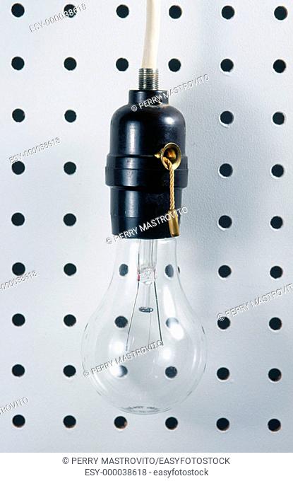 Clear light bulb in black socket on white peg-board