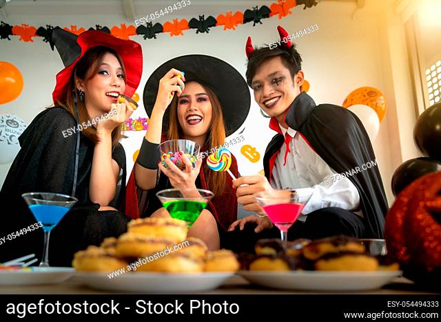 Group of young adult and teenager people celebrating a Halloween party carnival Festival in Halloween costumes with food and drink on table