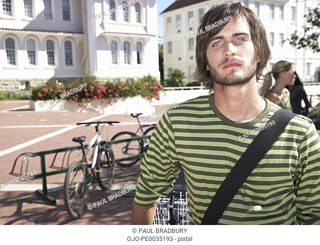 A young man standing by a bike rack