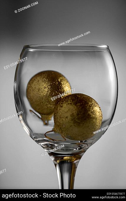Christmas balls-toys in an empty wine glass on a light background close-up
