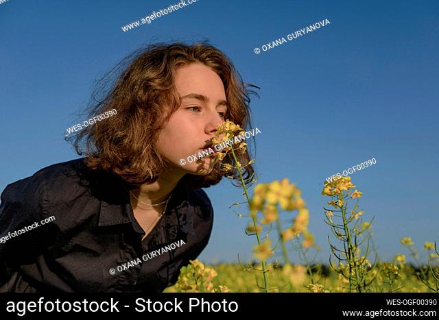 Portrait of teenage girl smelling blossom in rape field