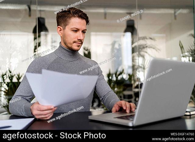 Confident businessman working on laptop at office