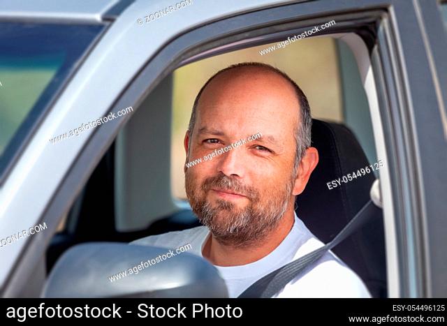 An image of a bearded man sitting in his car