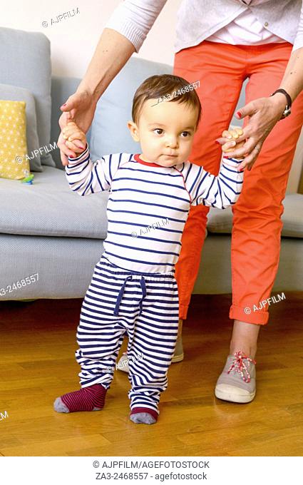 One year old baby trying to learn walking with his mother